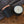 Load image into Gallery viewer, A black matte candle with a copper lid, placed on a textured surface, with an inset showing the candle's wick.