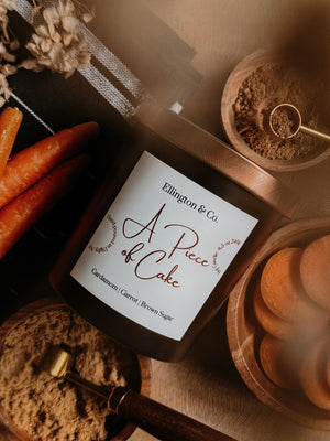 Bottle of 'A Piece of Cake' by Ellington & Co. with ingredients like carrots and brown sugar on a rustic background.