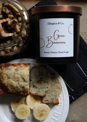 Candle labeled 'Ellington & Co. Gone Bananas' with banana slices and muffin on a plate.